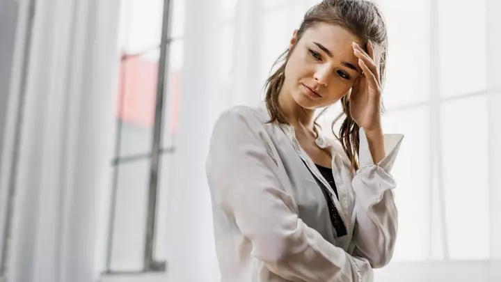 Сумна дівчина про щось думає, підперши голову рукою