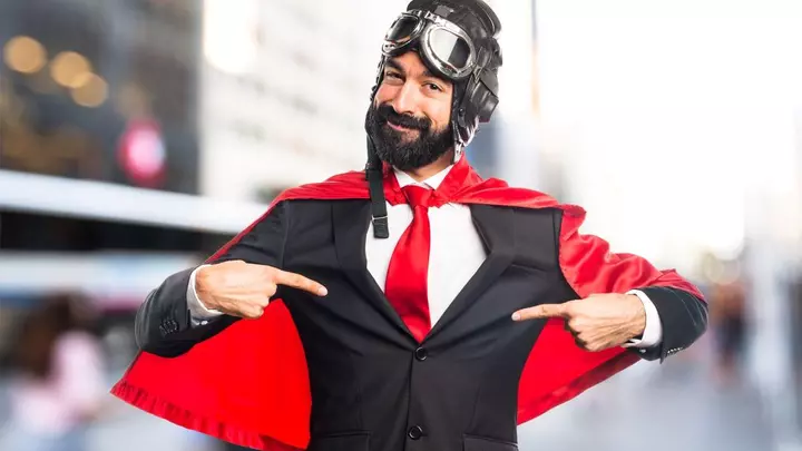 Гордий собою чоловік у шоломі з окулярами, костюмі та червоному плащі рятувальника