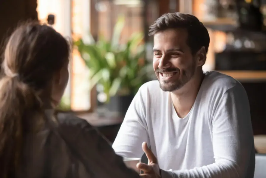Чоловік посміхається, дивлячись на жінку
