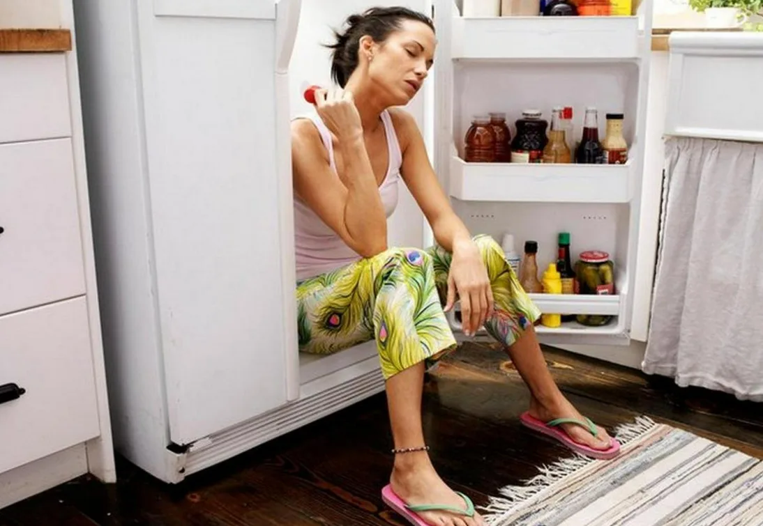 Жінка охолоджується, сидячи в холодильнику